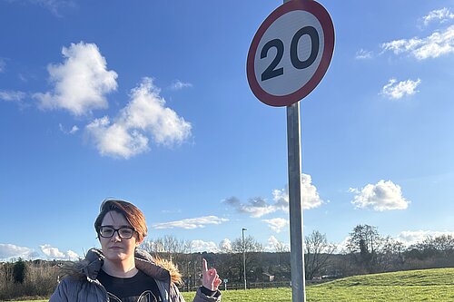 Candidate Sara Miles pointing to a 20 mph sign